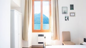 Une chambre d’hôtel avec une grande fenêtre, un lit, une chaise et un climatiseur fixé au mur.