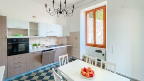 Une cuisine moderne avec des meubles blancs, un four noir et une table à manger avec des chaises.