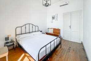 Ein Schlafzimmer mit einem Metallbettgestell, einem Nachttisch mit Lampe, einer kleinen Ablage und einer weißen Tür.