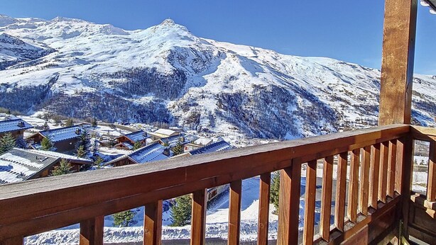 A snow-covered mountain with a wooden balcony overlooking a village.