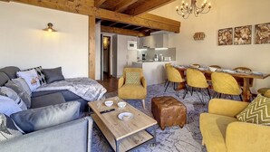 A modern living room with a sofa, a coffee table, and a dining area with yellow chairs.