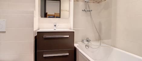 A modern bathroom with a bathtub, a vanity with a mirror, and a shower.
