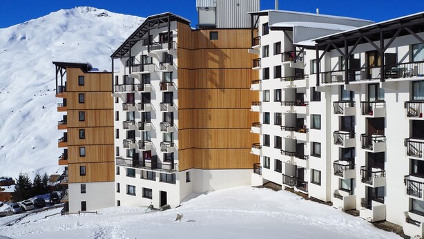 Un hotel moderno a più piani con balconi, immerso in una zona montuosa innevata.