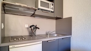 Una cucina compatta con forno a microonde, fornelli e lavello.