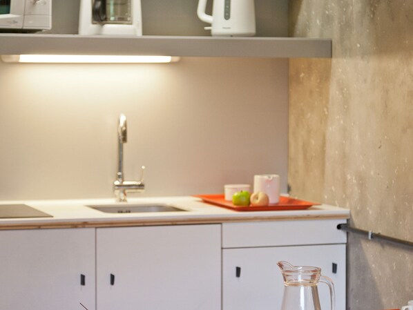 A modern kitchen with white cabinets, a stainless steel sink, and a glass pitcher on the counter.