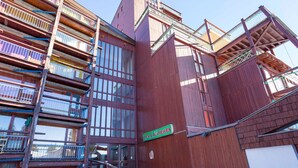 Un immeuble en bois à plusieurs étages, doté de balcons et d’une enseigne indiquant « LES LAUZIÈRES ».