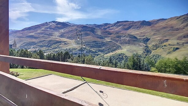 Un balcón con vistas a un paisaje montañoso, que incluye una carretera y un edificio a lo lejos.