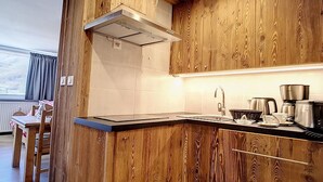 Cocina moderna con armarios de madera, extractor de acero inoxidable y encimera con fregadero y cafetera.