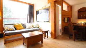 Ein gemütliches Wohnzimmer mit Sofa, Couchtisch und Esstisch aus Holz.