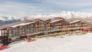 Un hôtel à étages, doté de balcons et offrant une vue sur des montagnes enneigées.