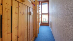 Un couloir aux murs lambrés et doté d’un tapis bleu, qui mène à une porte avec une fenêtre.