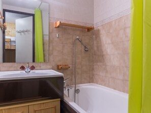 A bathroom with a bathtub, a shower, a sink, and a mirror.