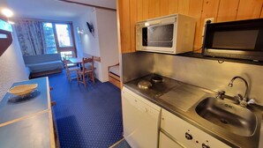 Une petite cuisine équipée d’un four à micro-ondes, d’une cuisinière et d’un évier.