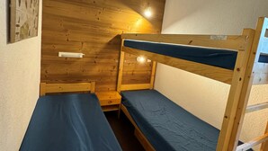 Ein Schlafraum mit Etagenbetten, Holzwänden und einem kleinen Tisch.