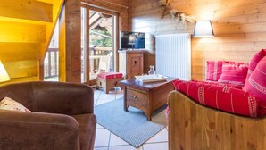 Een gezellig houten chaletinterieur met een bank, een houten tafel en een televisie.