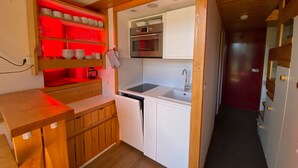 Una cocina compacta con armarios de madera, un microondas y un lavamanos.