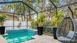Uma área de piscina com uma cadeira suspensa e plantas em vasos.