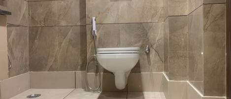 A bathroom with a toilet, a shower, and a hand dryer.