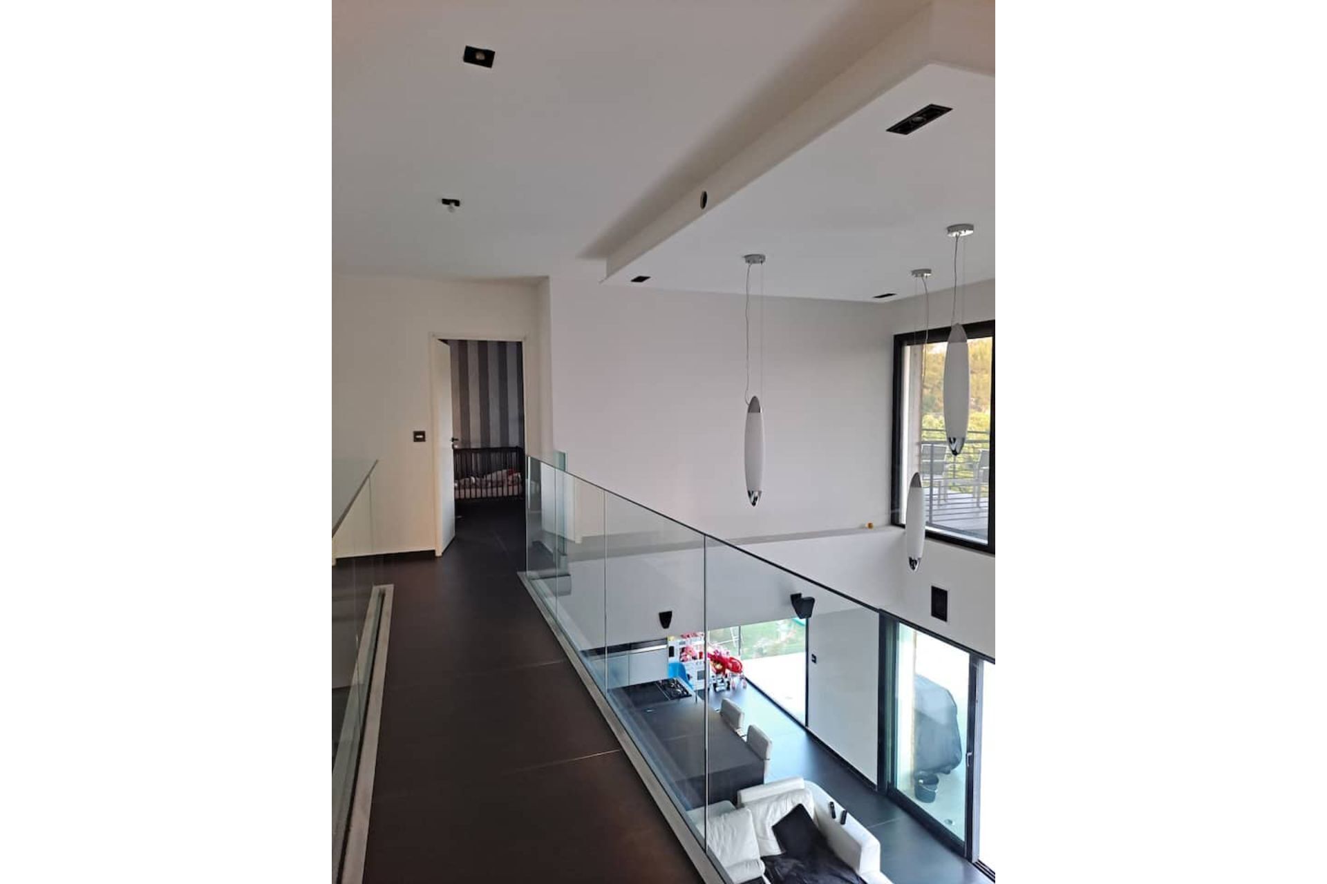Un intérieur moderne avec une balustrade en verre, un escalier et une vue sur l’extérieur.