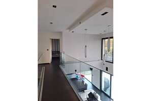 Um interior moderno com guarda-corpo de vidro, escada e vista para o exterior.