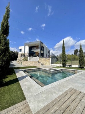 Uma casa moderna de dois andares, com fachada de pedra, piscina e deck de madeira.