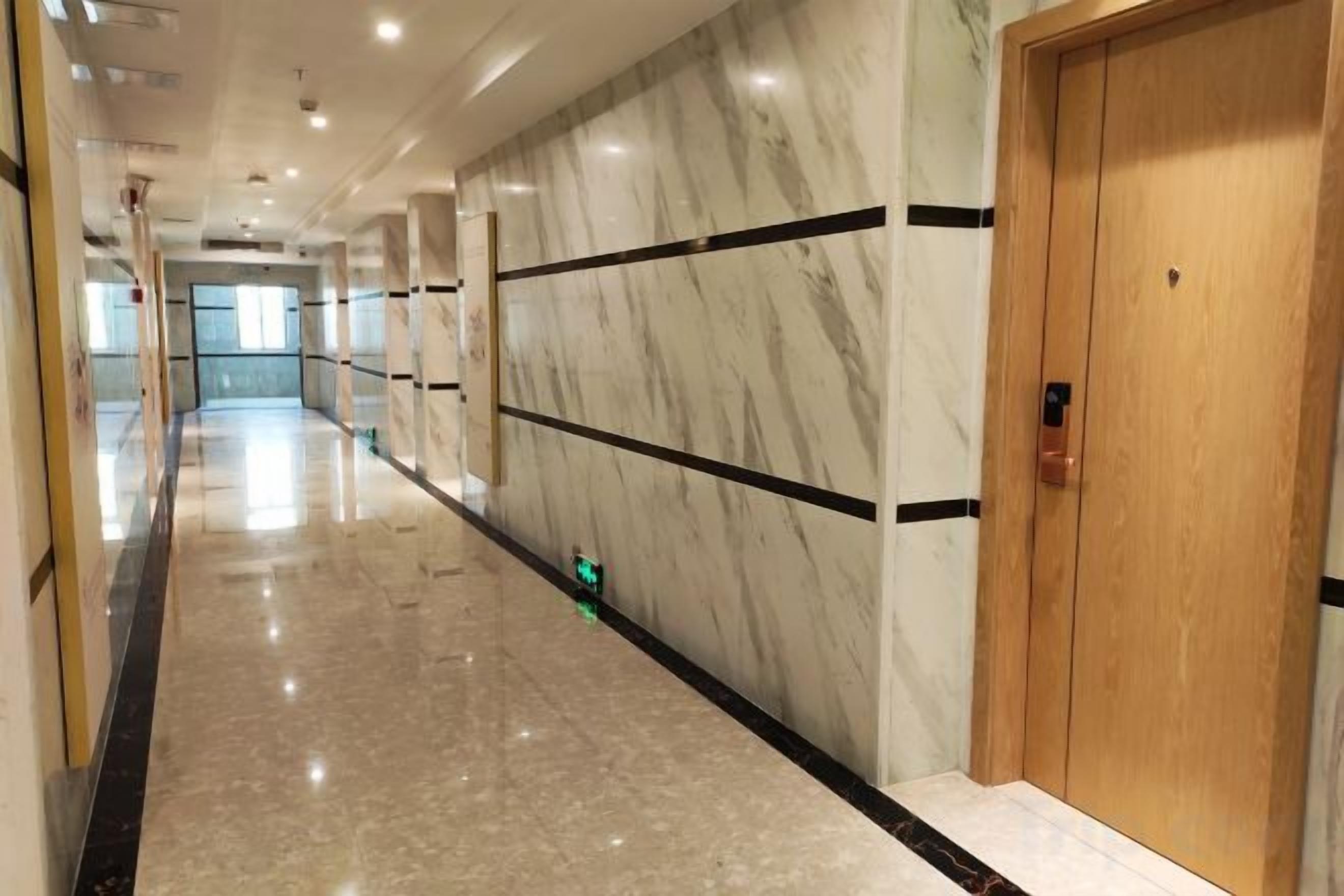 A hallway with marble walls and a wooden door.