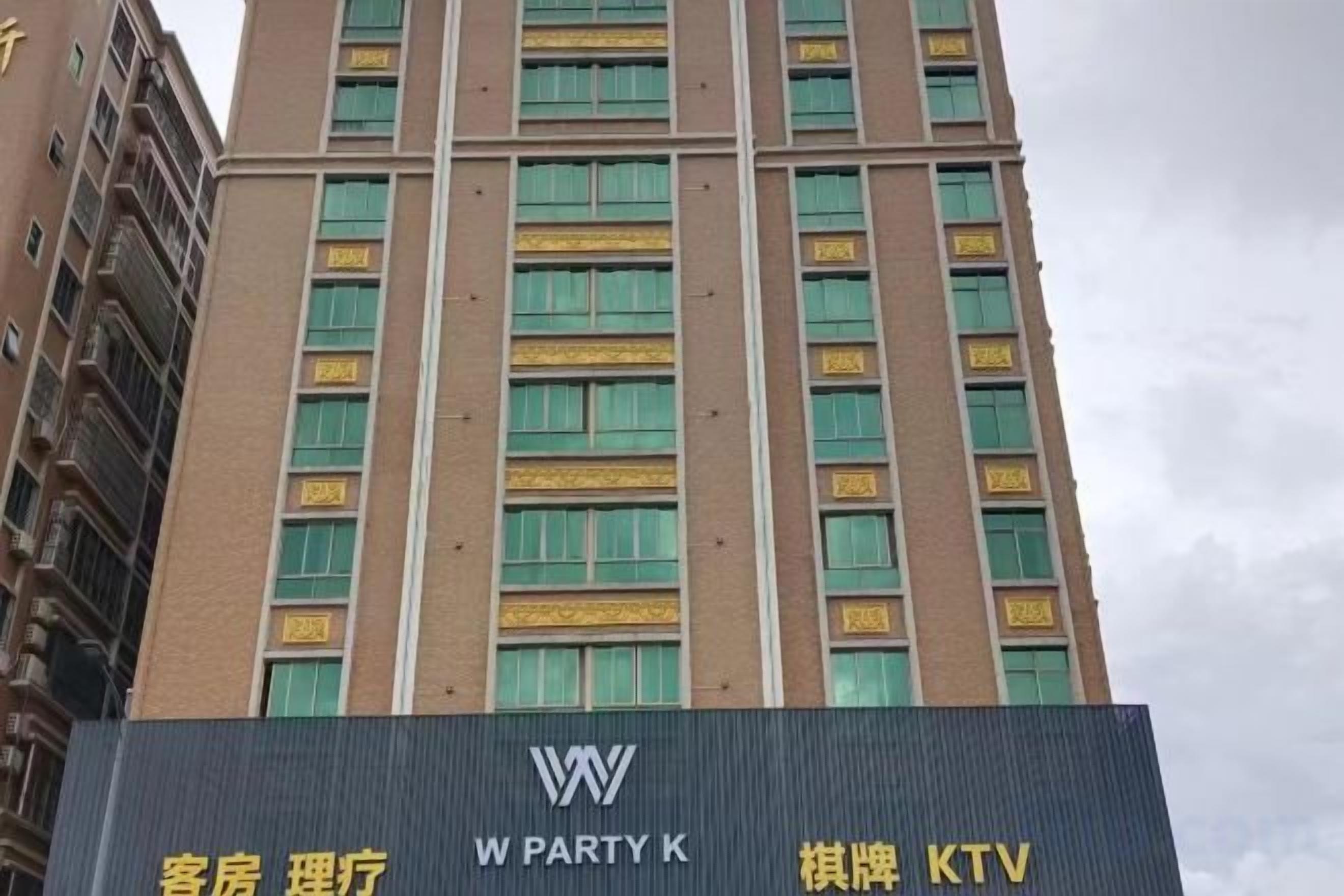 A tall building with multiple windows and a sign with 'W PARTY K' and 'KTV' indicating a hotel with a party room and karaoke facilities.