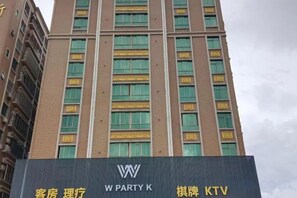 A tall building with multiple windows and a sign with 'W PARTY K' and 'KTV' indicating a hotel with a party room and karaoke facilities. - Xin Zhenhao Business Hotel (Shantou)