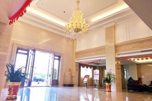 A hotel lobby with a chandelier, potted plants, and a reception desk. - Xin Zhenhao Business Hotel (Shantou)