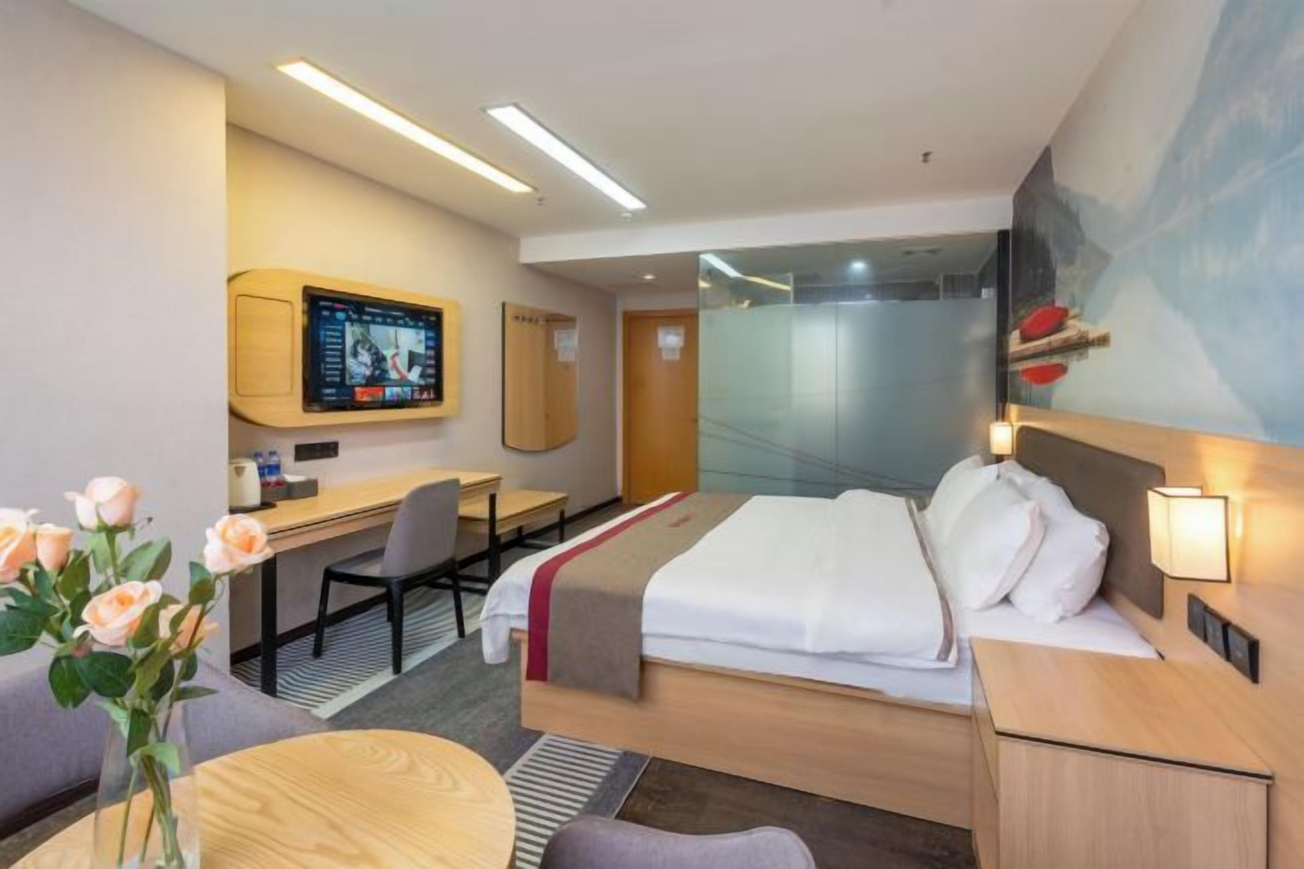 A modern hotel room with a bed, desk, and TV.