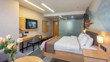 A modern hotel room with a bed, desk, and TV.