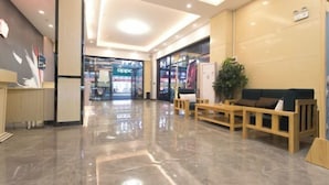 Un hall d’entrée moderne avec un sol en marbre poli, des sièges en bois et un comptoir d’accueil.