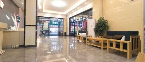 Um lobby moderno com piso de mármore polido, assentos de madeira e um balcão de recepção.