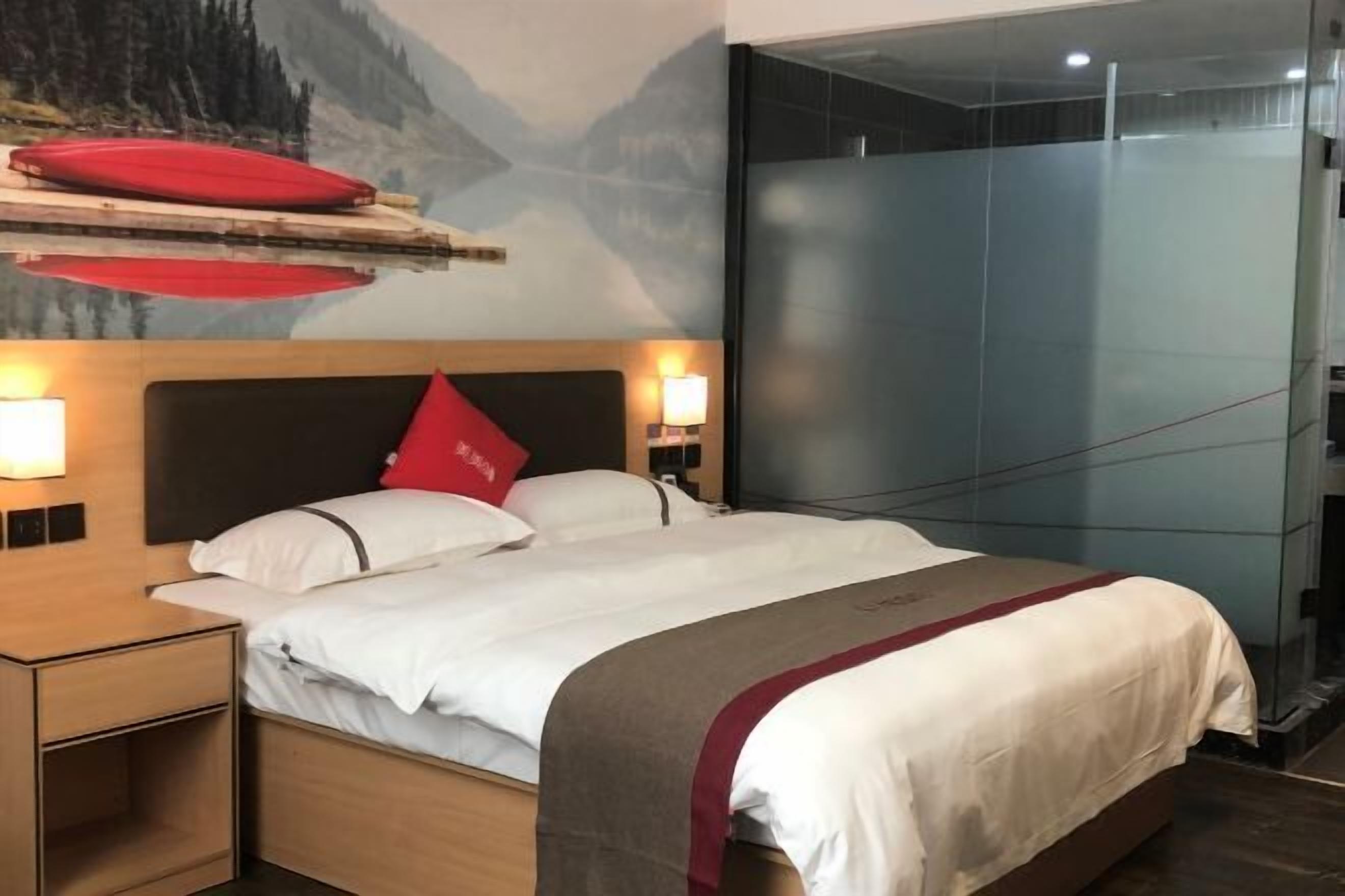 A hotel room with a bed, nightstands, and a glass partition.