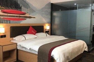 A hotel room with a bed, nightstands, and a glass partition.