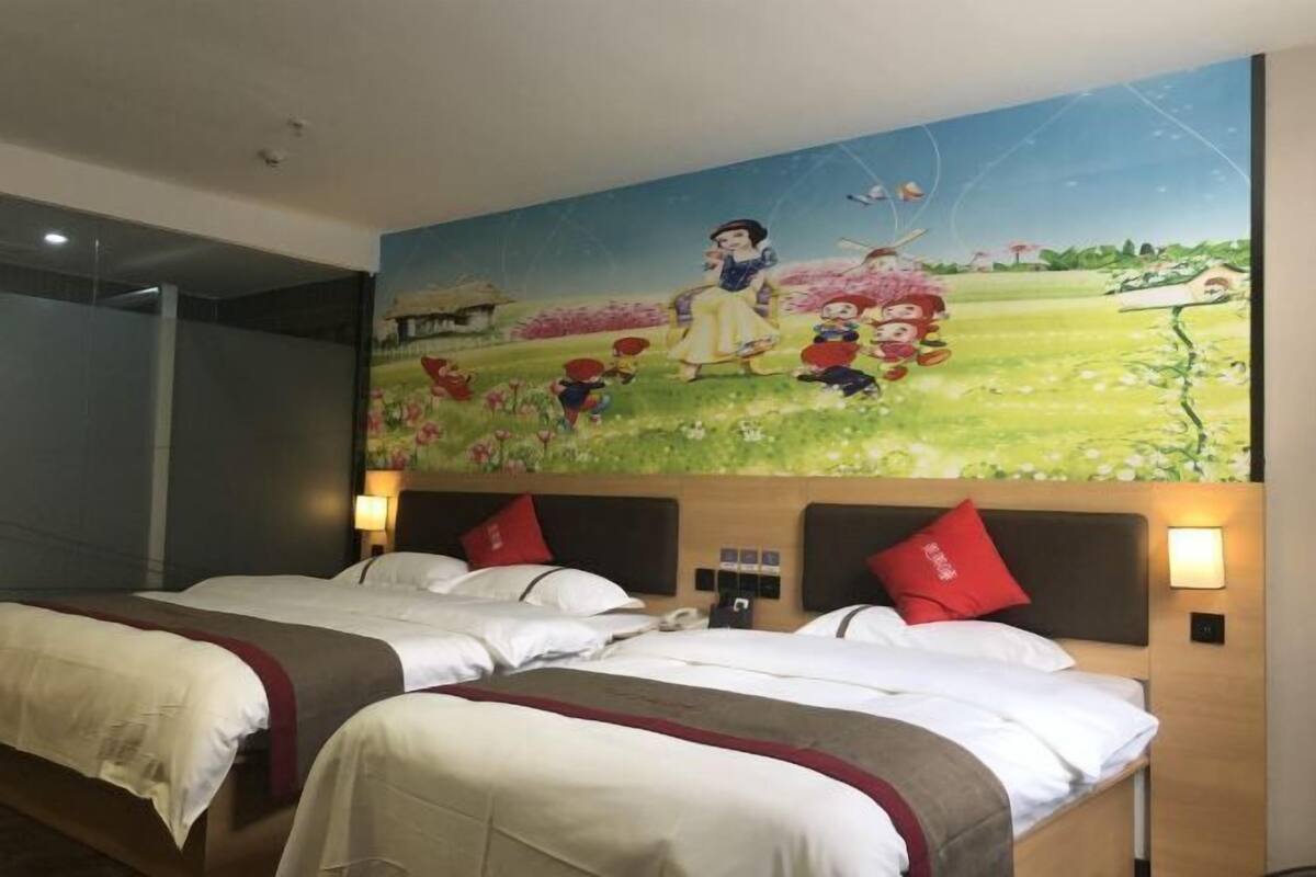 Une chambre d’hôtel avec deux lits, une fresque représentant Blanche-Neige et des enfants, et une cabane au toit de chaume.