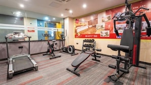 Une salle de sport équipée de tapis de course, de vélos elliptiques et de matériel de musculation.