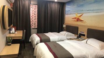 A hotel room with two beds, a desk, a chair, a TV, and a beach-themed wall mural.