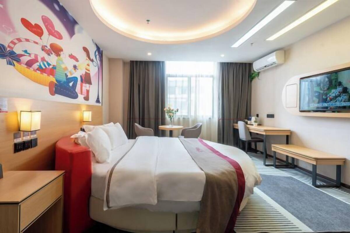 Une chambre d’hôtel équipée d’un lit, d’un bureau, d’une télévision et d’un climatiseur fixé au mur.
