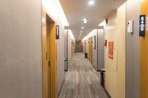 Pasillo de hotel con puertas numeradas 8407 y 8408, pisos alfombrados y señalización de salida de emergencia.