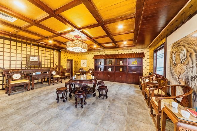 A traditional interior with wooden furniture, a central round table, and a tiger mural.