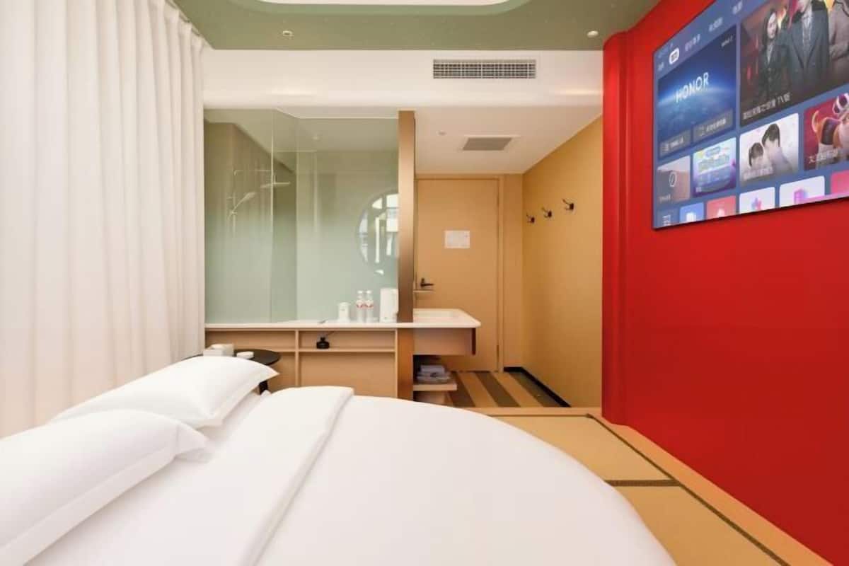 Ein Hotelzimmer mit Bett, Schreibtisch, Spiegel und einem Fernseher, der verschiedene Sender anzeigt.