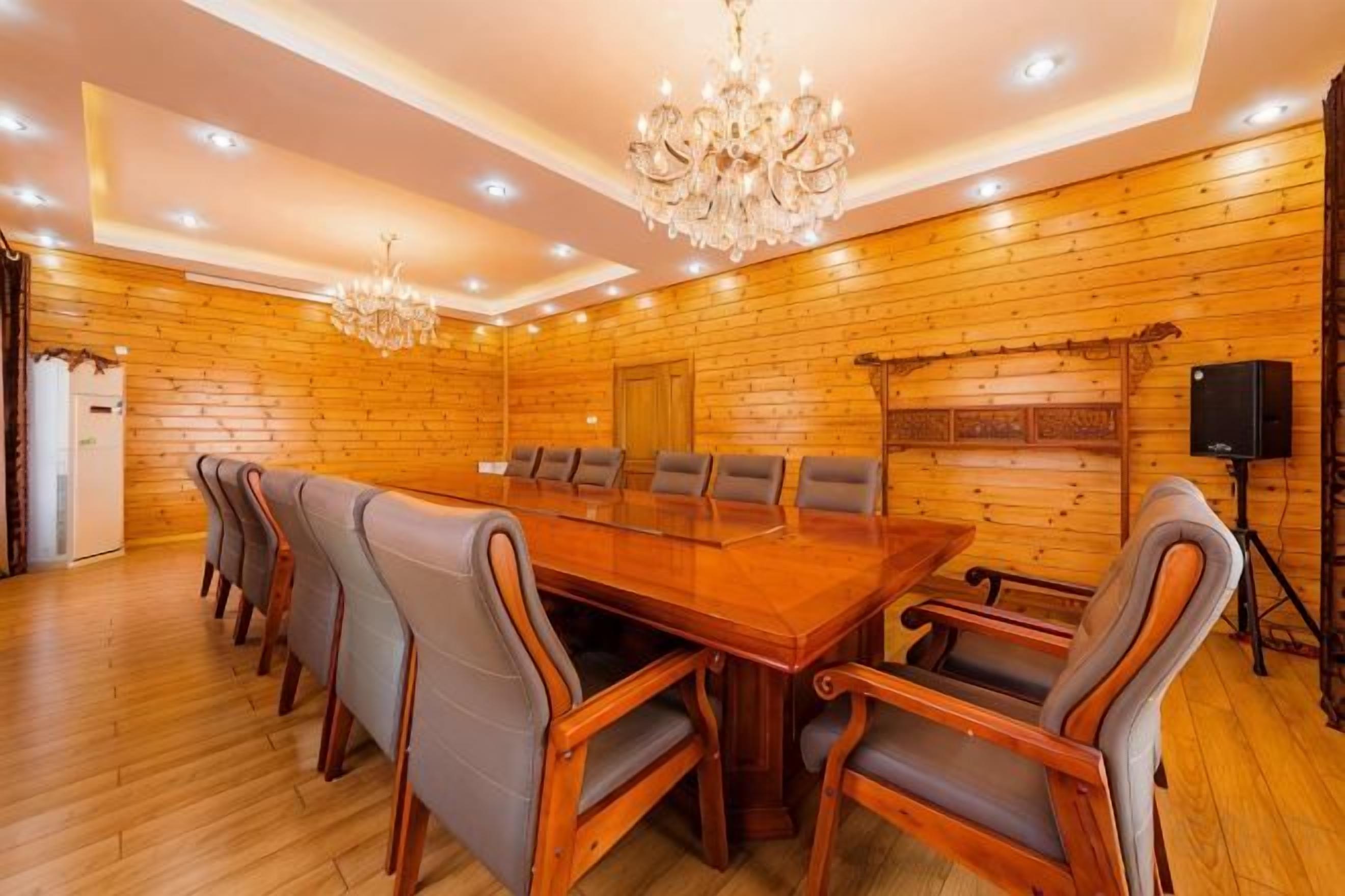 Un salón de conferencias con una larga mesa de madera, varias sillas y una araña de cristal.