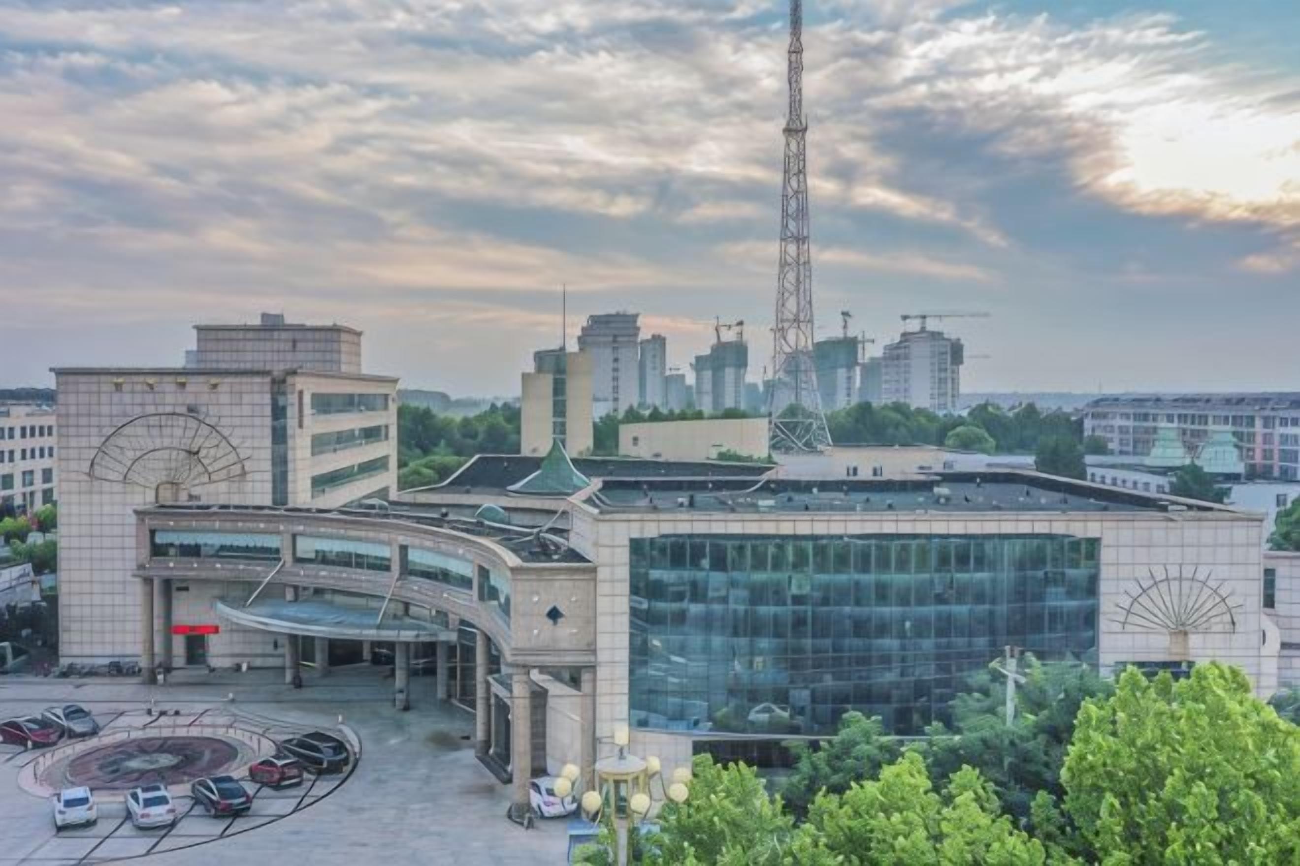 Un edificio moderno con fachada de vidrio, zona de estacionamiento y vistas al horizonte de la ciudad.