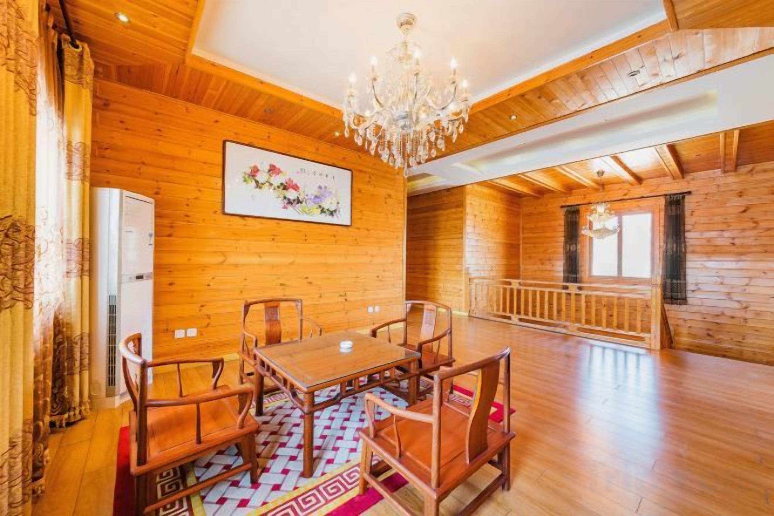 A wooden interior with a dining table and chairs, a chandelier, and a wooden floor.