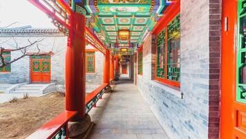 A corridor with traditional Chinese architecture, featuring red columns and ornate ceiling decorations.