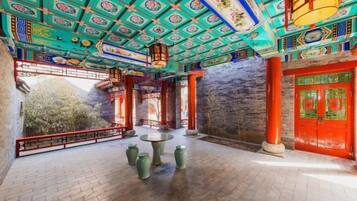 A traditional Chinese courtyard with a tiled floor, a round table, and red doors.