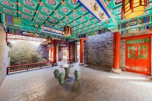 A traditional Chinese courtyard with a tiled floor, a round table, and red doors.