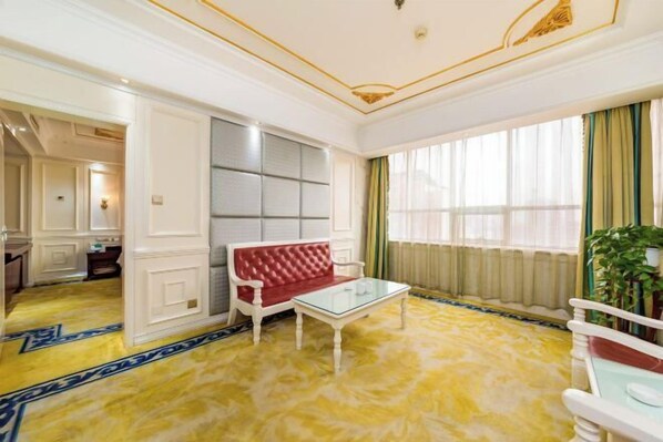 A room with a red sofa, a glass coffee table, and a yellow patterned carpet. - Succeed Hotel (Tangshan)