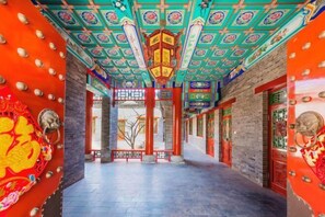 A corridor with traditional Chinese architecture, featuring ornate ceiling designs and red doors. - Succeed Hotel (Tangshan)